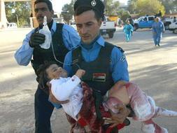 Dos policías trasladan en brazos a una niña herida en el atentado de Kirkuk./ Afp