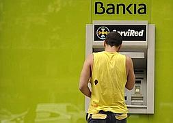 Un joven saca dinero en una sucursal de Bankia. / Archivo