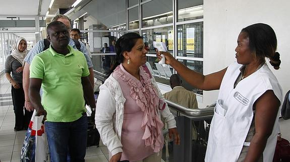 Una voluntario mide la temperatura de los viajeros internacionales a su llegada a Costa de Marfil. 