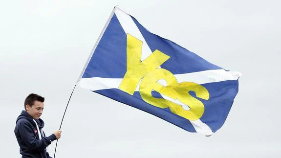 Un joven con una bandera escocesa con un 'Sí' escrito en ella. 