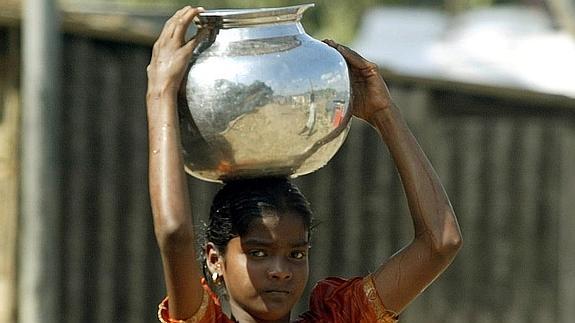 Una chica india transporta agua potable en un recipiente. 