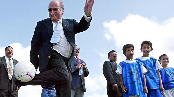 Joseph Blatter controla un balón delante de unos niños.