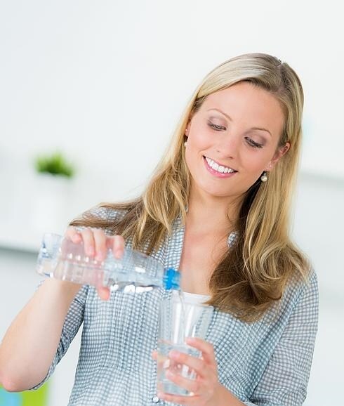 Una mujer se sirve un vaso de agua. 