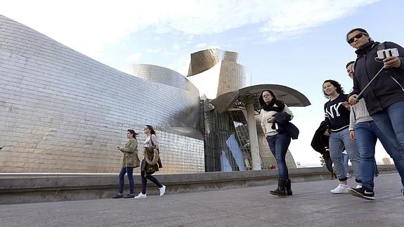 Varias personas pasean en la inmediaciones del museo Guggenheim en Bilbao.