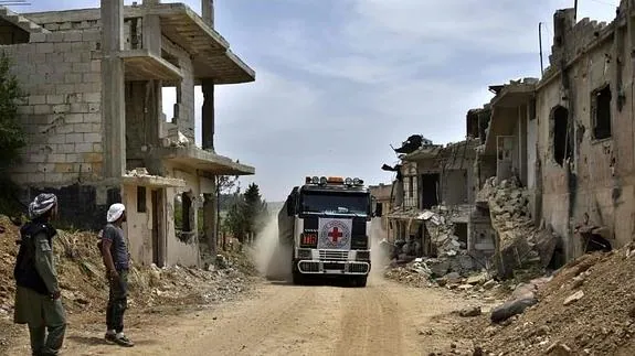 Un camión de la Cruz Roja, entre edificios derruidos en Homs. 