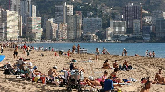 Turistas disfrutando del sol en la playa de Benidorm.