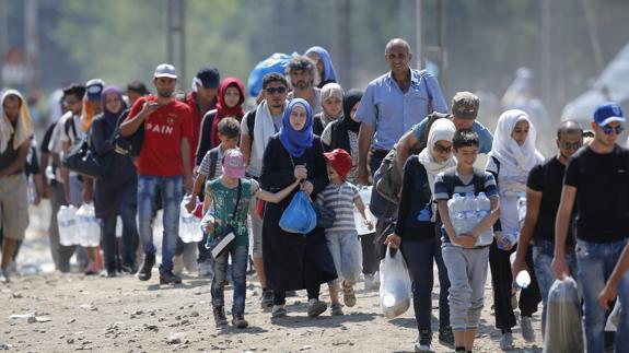 Refugiados cruzan la frontera entre Macedonia y Grecia.