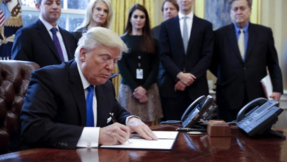 Trump firma un documento. 