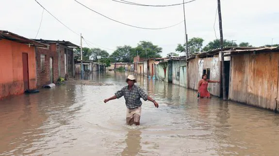 Un hombre trata de cruzar una calle inundada en la región de Piura, en la costa norte de Perú. 