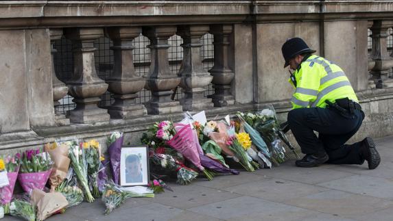 Un policía coloca flores en honor a una de las víctimas del ataque en Londres.