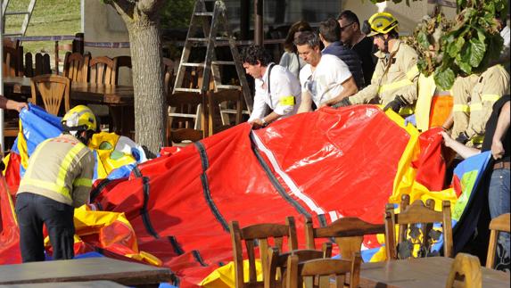 Varios operarios y bomberos retiran el castillo hinchable del restaurante Mas Oller, de Caldes de Malavella (Gerona).