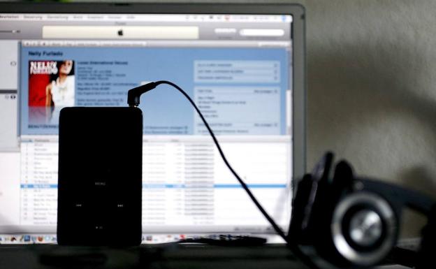 Reproductor de música iPod colocado frente a un ordenador portátil. 