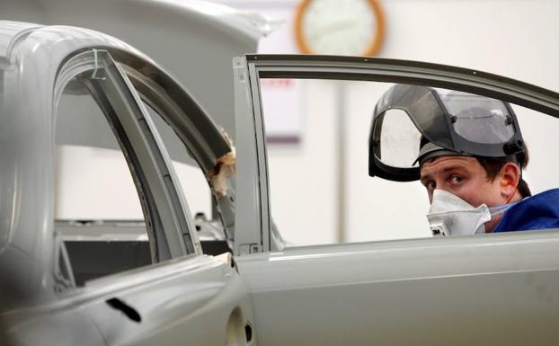 Un joven repara un automóvil. 