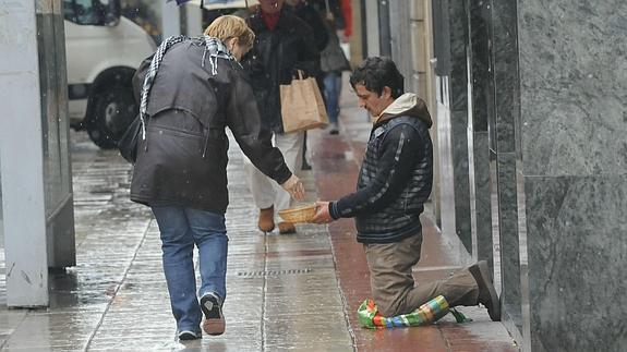 Un hombre pide en la calle. 