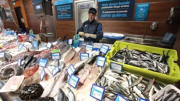 Una pescatera elimina las vísceras de una partida de anchoas para venderlas ya limpias.
