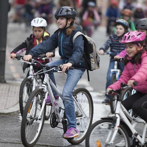 Tres niñas acuden al colegio en bici con casco.