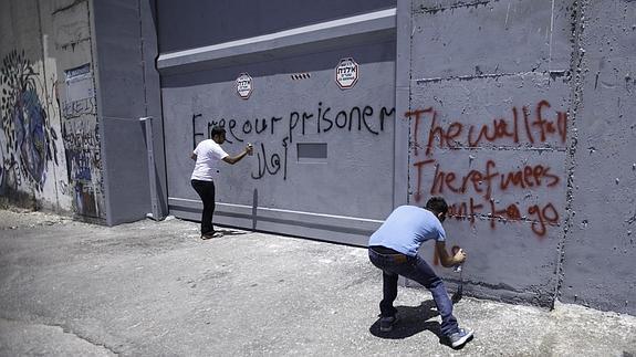 Dos activistas escriben varios lemas en el muro. 