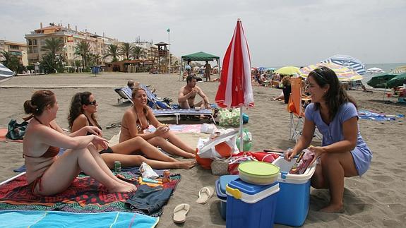 Grupo de jóvenes con sus neveras de comida en la playa.