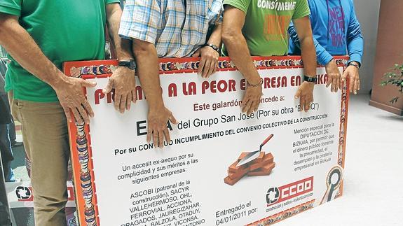 Cuatro de los seis despedidos, que prefieren guardar el anonimato "porque igual no nos llaman ya para más obras", posan con un cartel reivindicativo de CC OO.