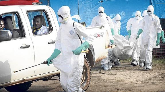 Un grupo de sanitarios traslada el cadáver de una mujer que murió por el ébola en Foya, una localidad de Liberia.