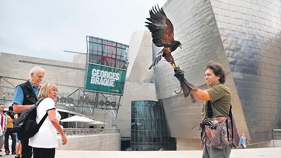 Dos turistas admiran la majestuosidad de 'Morgan', el águila encargada de espantar las palomas de los recovecos del Guggenheim.