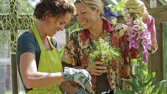 Dos mujeres cuidan de unas plantas. 