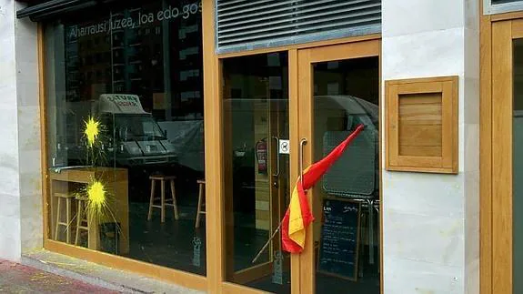 Pintura amarilla y una bandera española en la puerta del batzoki.