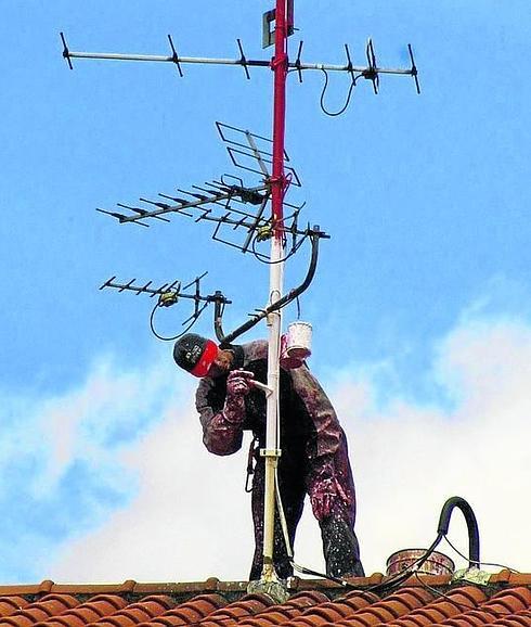Un operario instala una antena de televisión.