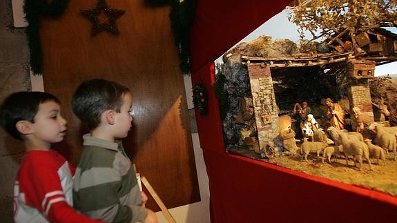 Dos niños observan un belén.