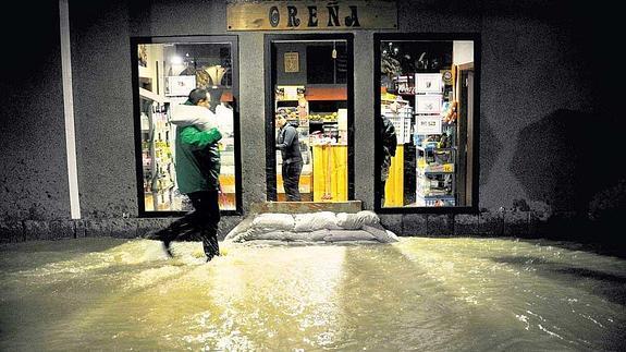 Un hombre coloca en la noche de ayer sacos terreros para evitar que entre el agua en un comercio de Zalla.