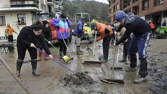 Vecinos de Zalla limpiando el barro de las calles tras la riada. 