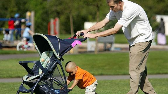 Un padre empuja el carrito con su hijo.