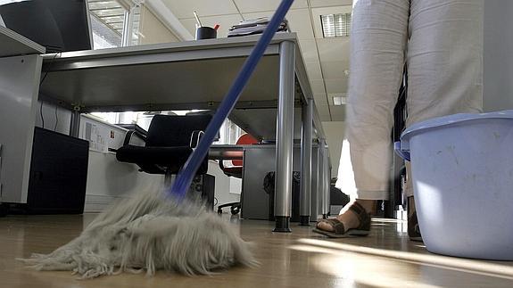 Una mujer pasando la fregona en una oficina.