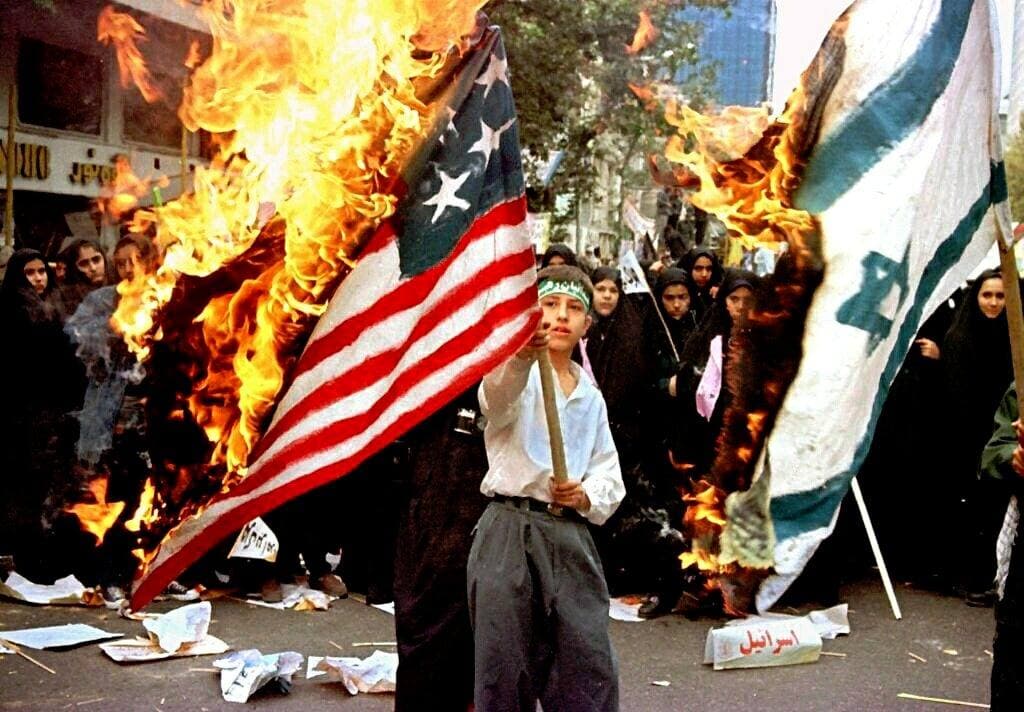 Jóvenes iraníes queman banderas estadounidenses frente a la embajada de ese país en Teherán, en 1997.