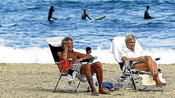 Playeros y surfistas disfrutan del buen tiempo otoñal en el arenal donostiarra de La Zurriola.