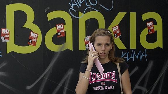 Una mujer ajena a la información ante un logo de Bankia en Madrid. 