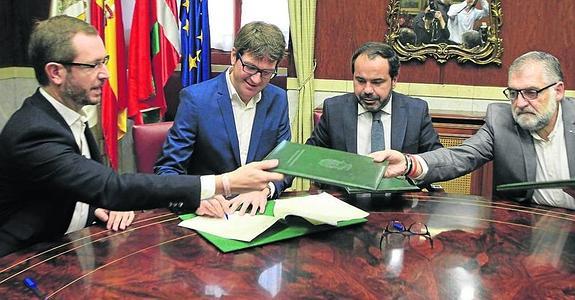 Peio López de Munain (PSE) pasa una carpeta a Javier Maroto (PP) y Gorka Urtaran (PNV) firma el pacto junto a Pascal Gómez (SEA). 