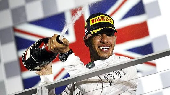 El piloto de F1 Lewis Hamilton agita una enorme botella de champán tras una victoria.