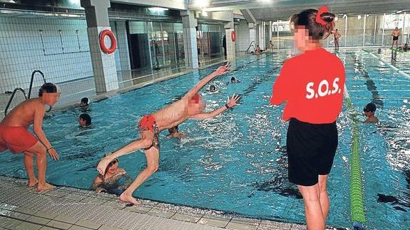 Una fotografía de archivo muestra a una monitora de natación con un grupo infantil en una piscina municipal.