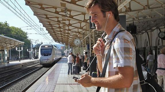 Un pasajero escucha música antes de coger un tren.