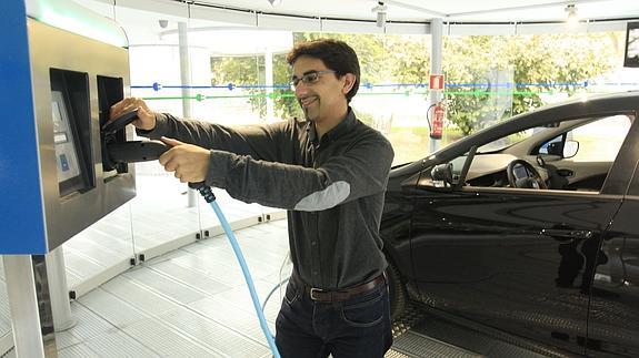 Un hombre carga un coche eléctrico. 