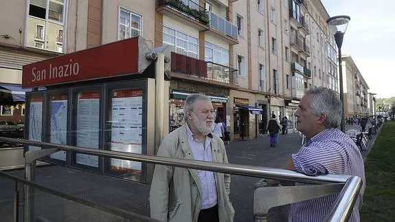 Dos de los miembros de la plataforma vecinal charlan en la boca de acceso al suburbano.