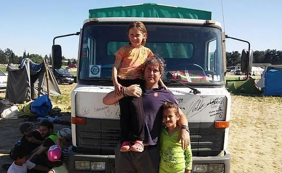 Álvaro posa con dos niñas del campamento. Otros refugiados se cobijan a la sombra del camión.