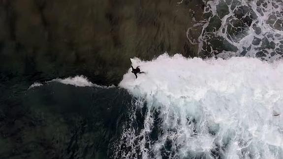 Un surfista tomando una ola, a vista de dron. 