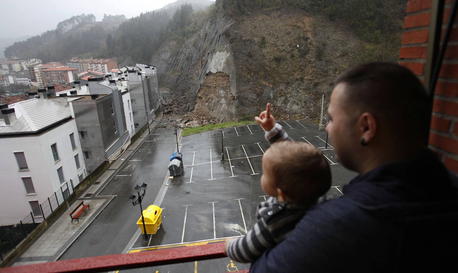 Un padre y su hijo observan desde su casa la ladera de Kamiñalde en Ondarroa.