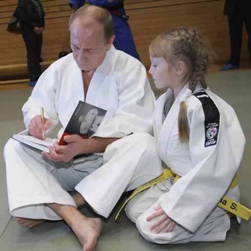 Putin, con su inseparable kimono, dedica un ejemplar a una alumna. 
