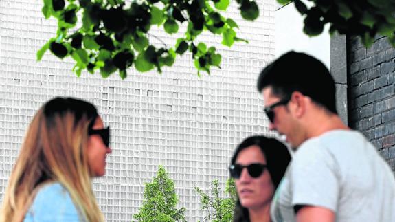 Varios estudiantes charlan junto a la fachada de la biblioteca que mira hacia la Plaza Euskadi, en la que se aprecian los desconchones.