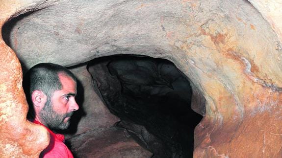 Garate examina los grabados paleolíticos de una cueva.
