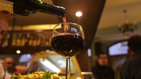 Camarero de un bar bilbaíno vierte vino en una copa.