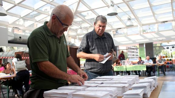 Dos hombres preparan su voto antes de depositarlo en la urna este domingo.